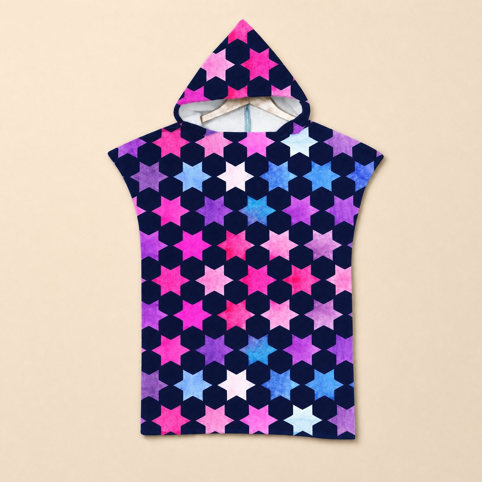 Poncho serviette à capuche enfant · Étoiles multicolores, posé à plat sur un fond uni, avec son motif d'étoiles roses