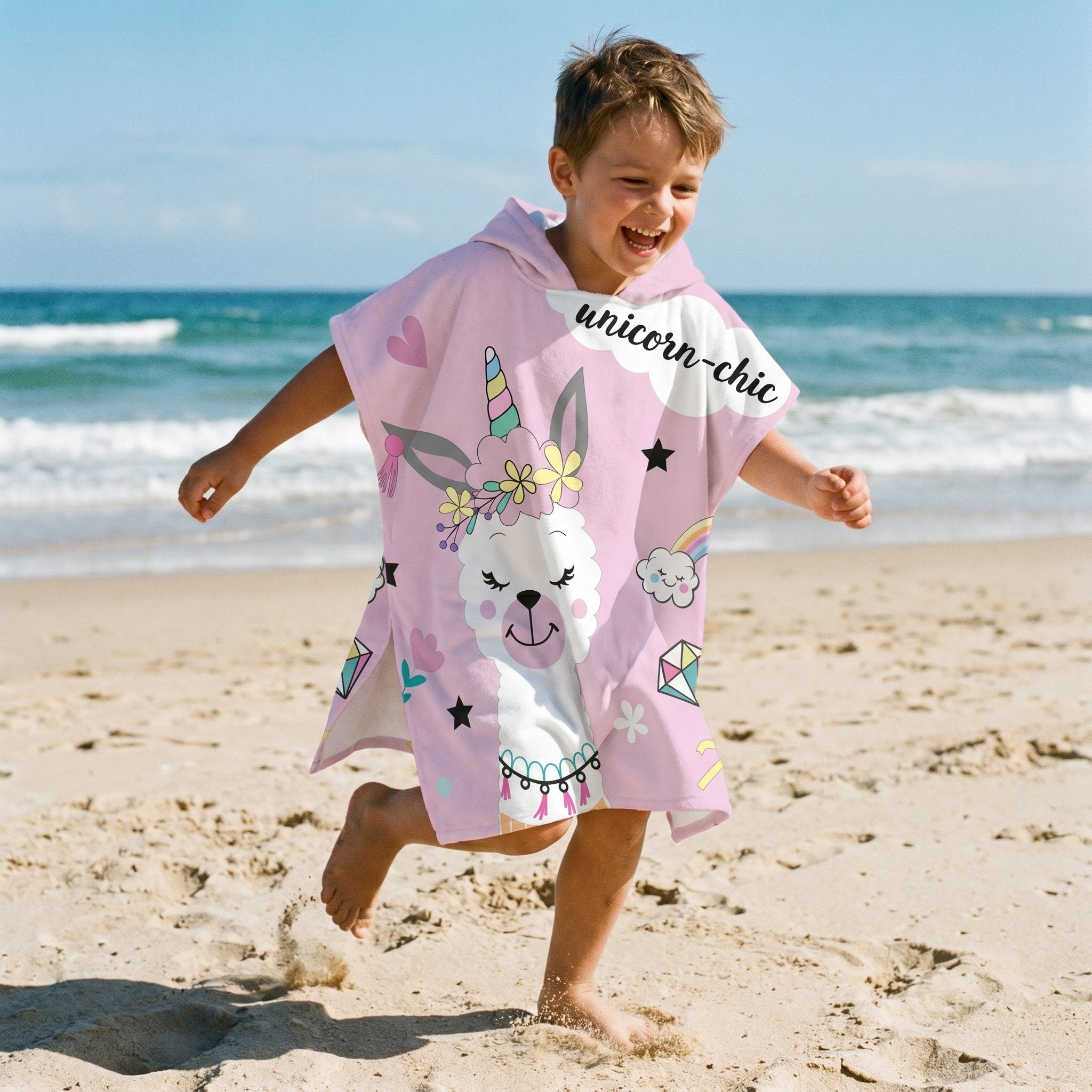 Poncho serviette a capuche motif lama licorne, porte par un enfant courant sur la plage.