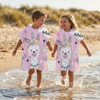 Poncho serviette a capuche motif lama licorne, porte par deux enfants marchant dans l'eau de mer.