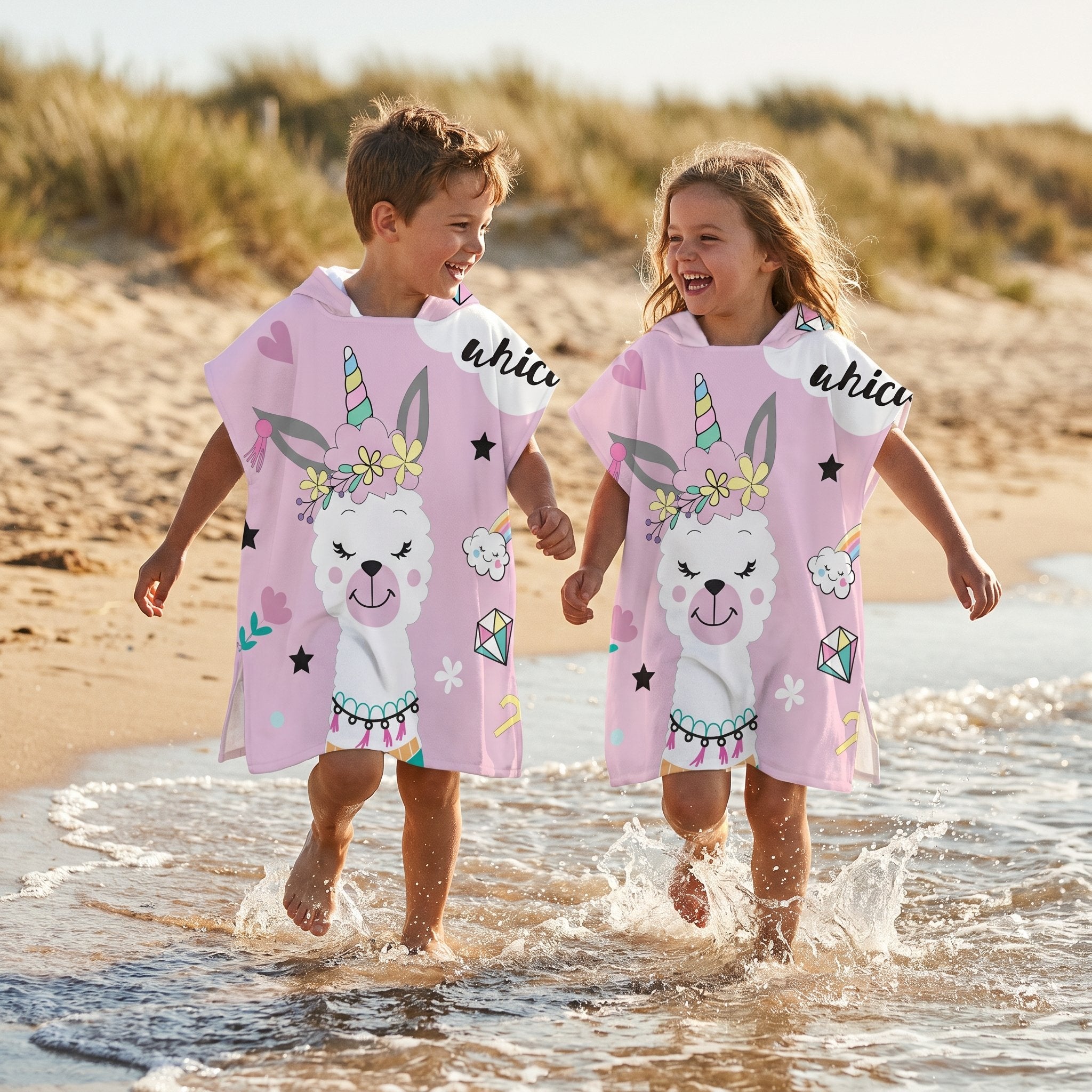 Poncho serviette a capuche motif lama licorne, porte par deux enfants marchant dans l'eau de mer.