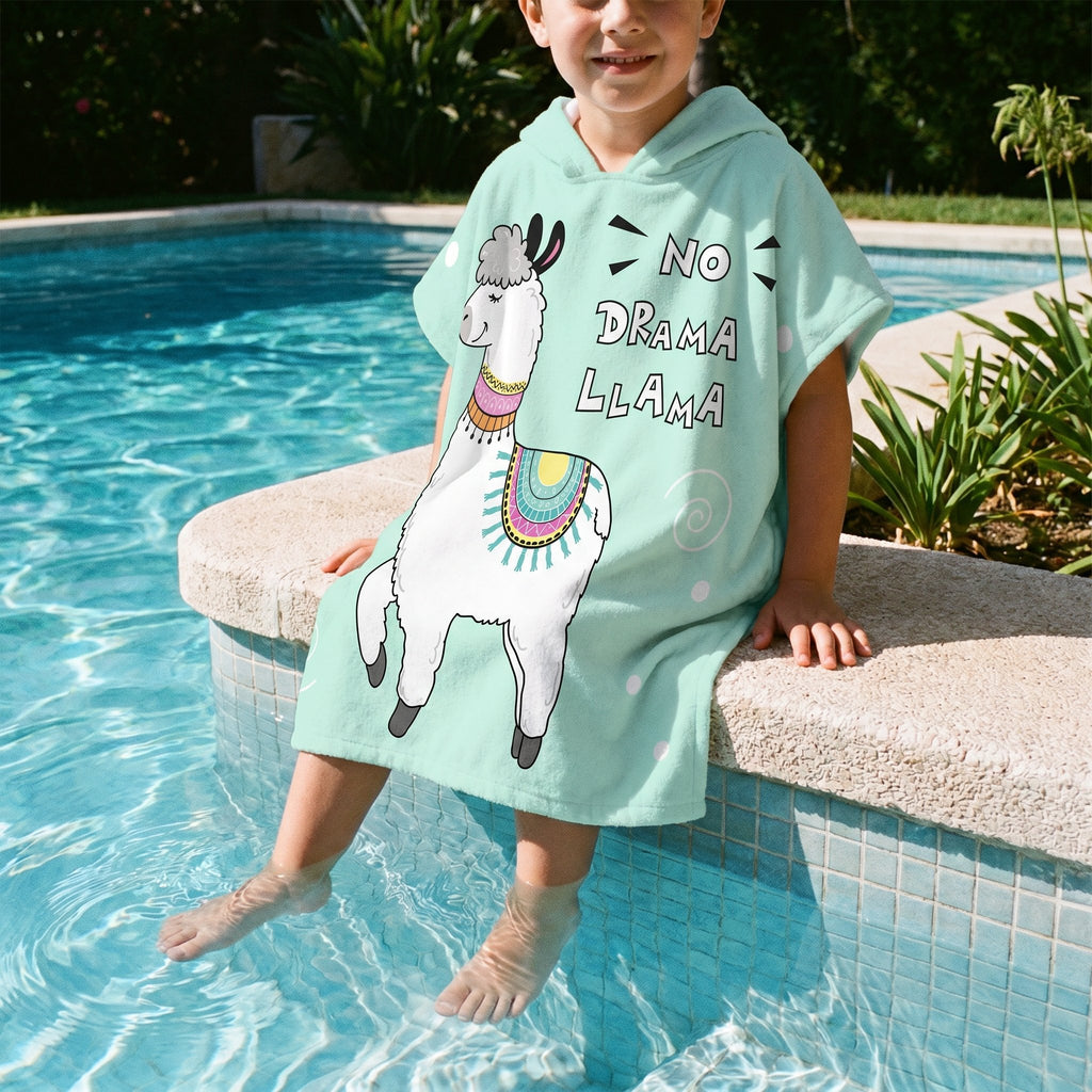 Poncho serviette à capuche motif lama menthe, porté par un enfant assis au bord d'une piscine.