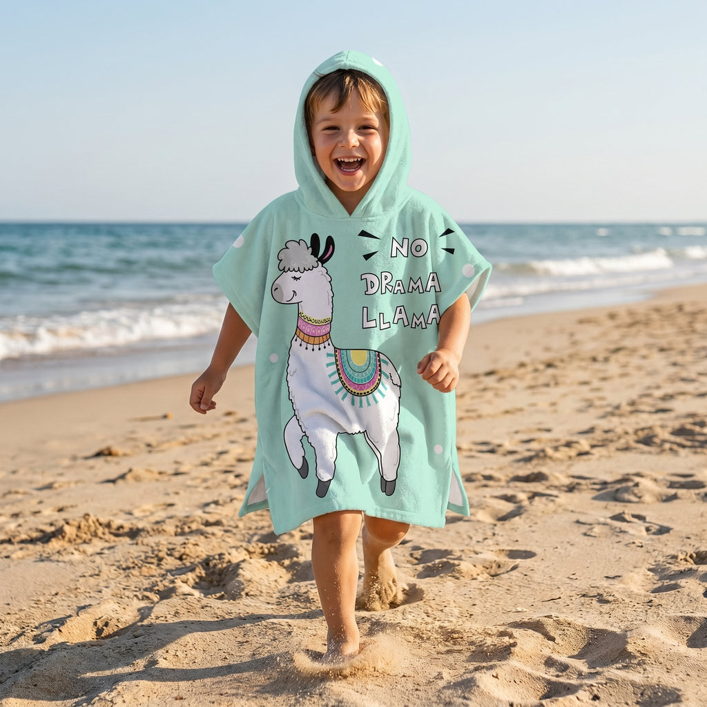 Poncho serviette à capuche motif lama menthe, porté par un enfant souriant courant sur le sable.