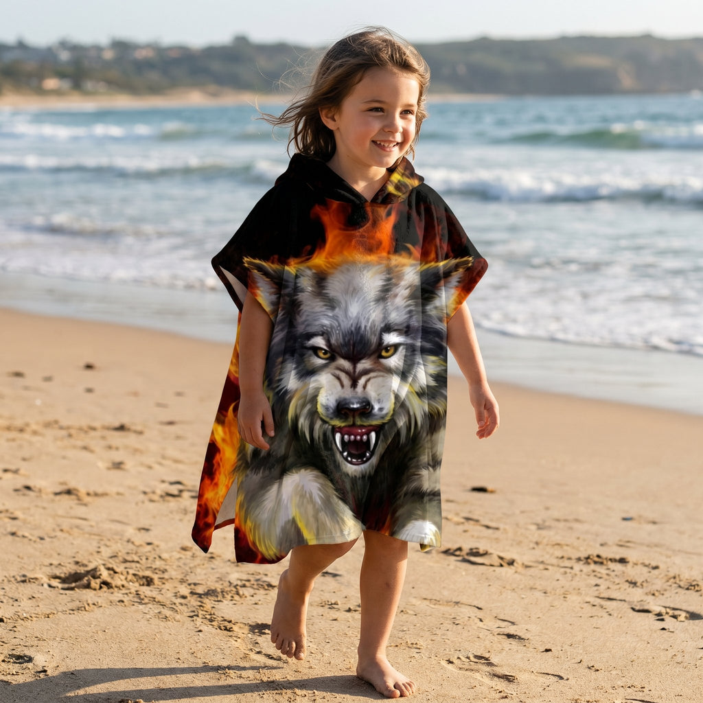 Poncho serviette a capuche motif Loup de feu, porte par une enfant souriante sur la plage.