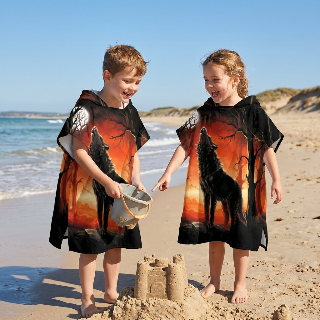 Poncho serviette a capuche motif loup forêt rouge porté par deux enfants souriants sur la plage.