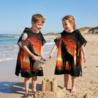 Poncho serviette a capuche motif loup forêt rouge porté par deux enfants souriants sur la plage.