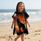 Poncho serviette a capuche motif loup forêt rouge porté par une enfant souriante marchant sur le sable.