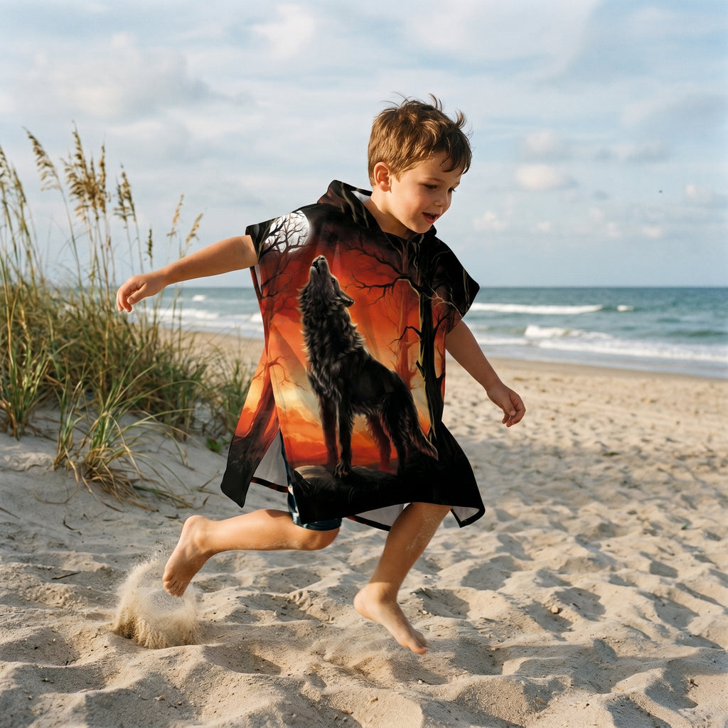 Poncho serviette a capuche motif loup forêt rouge porté par un enfant sautant joyeusement sur la plage.