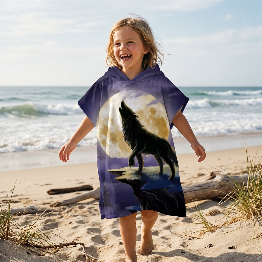 Poncho serviette a capuche motif loup lune violette, porte par une enfant souriante sur la plage.