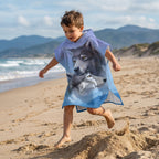 Poncho serviette a capuche motif loups, porté par un enfant en mouvement, courant et sautant sur le sable de la plage.