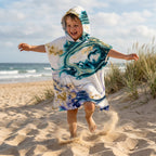 Poncho serviette a capuche motif marbre nuit dorée, porte par un garcon courant et sautant sur la plage.