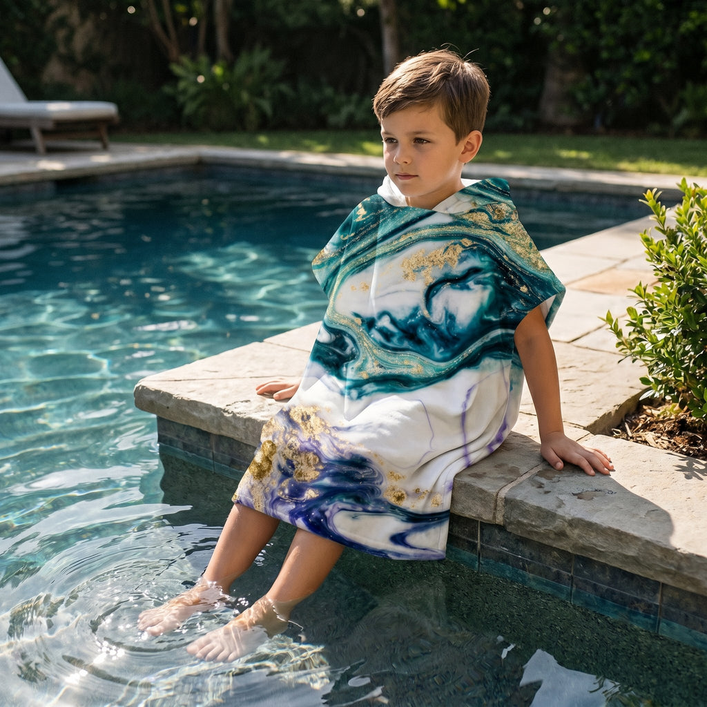 Poncho serviette a capuche motif marbre nuit dorée, porte par un garcon assis au bord d'une piscine.