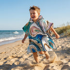 Poncho serviette a capuche motif marbre tourbillon cuivré, porté par un enfant rieur courant sur la plage.