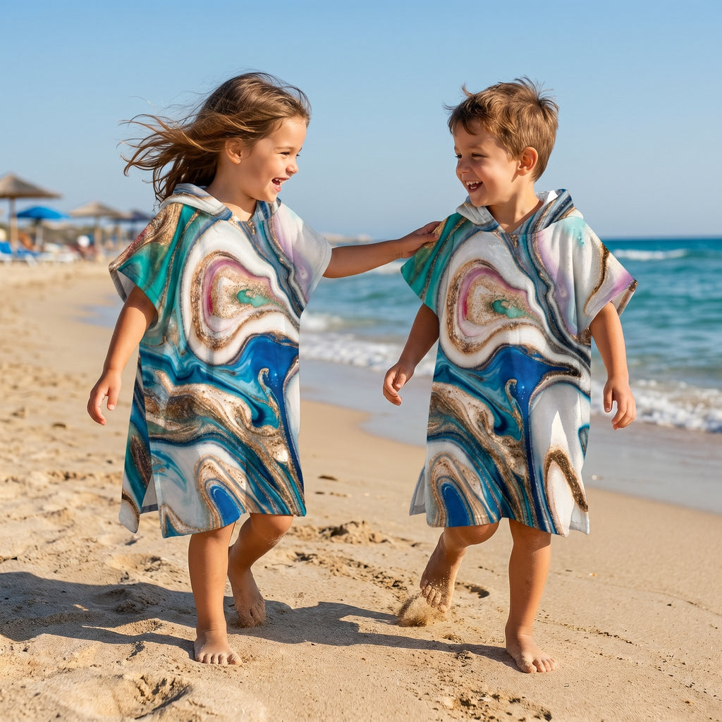 Poncho serviette a capuche motif marbre tourbillon cuivré, porté par deux enfants riant et marchant sur le sable.