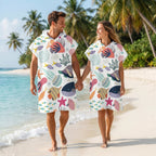 Poncho serviette a capuche motif Fonds marins colorés, porté par un couple marchant main dans la main sur la plage.