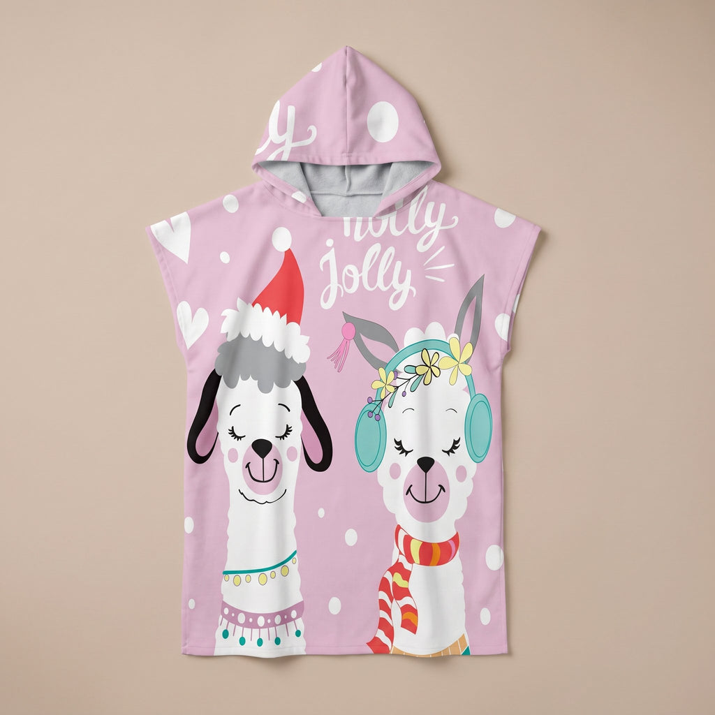 Poncho serviette à capuche motif lamas de Noël, présenté à plat sur un fond uni rose clair.