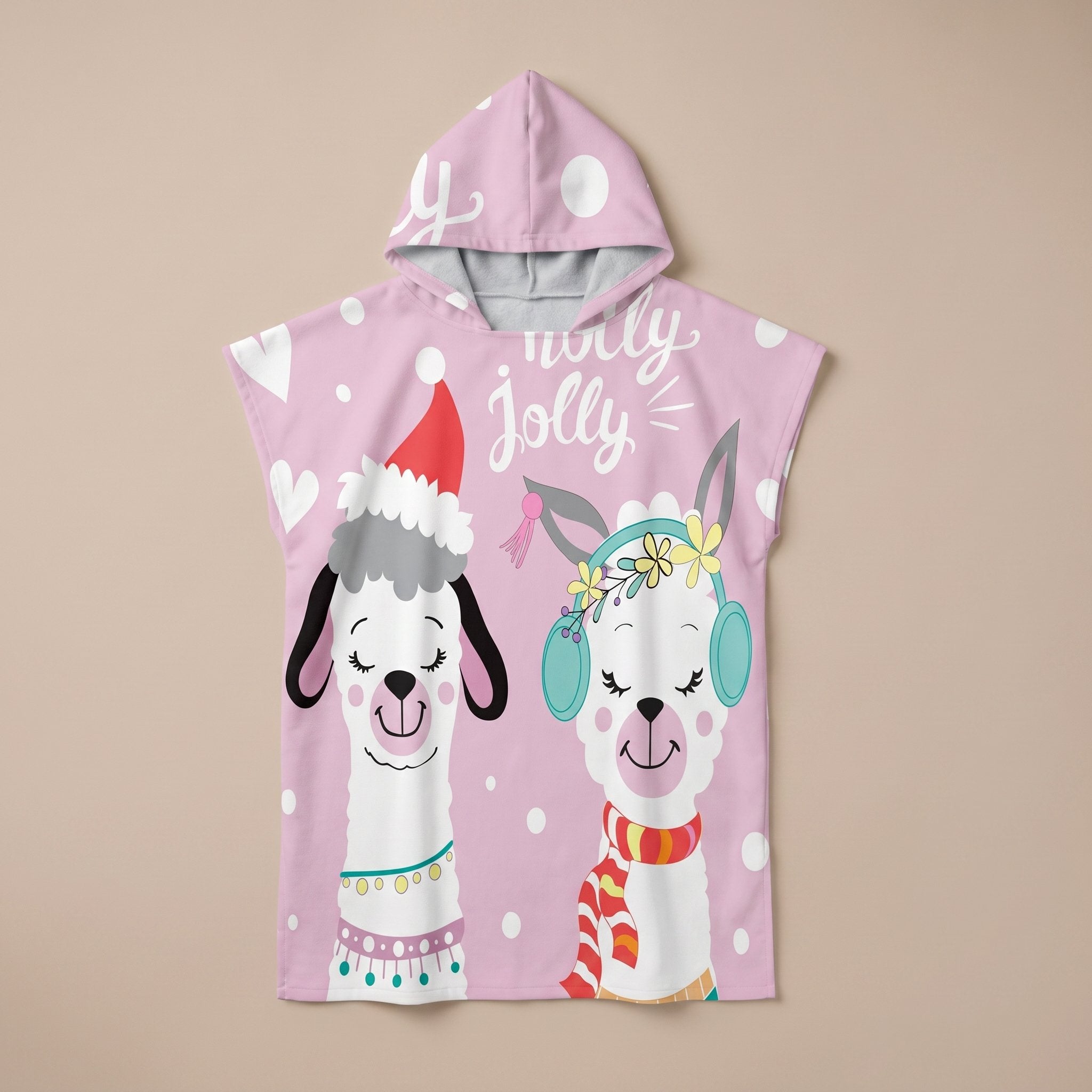 Poncho serviette à capuche motif lamas de Noël, présenté à plat sur un fond uni rose clair.