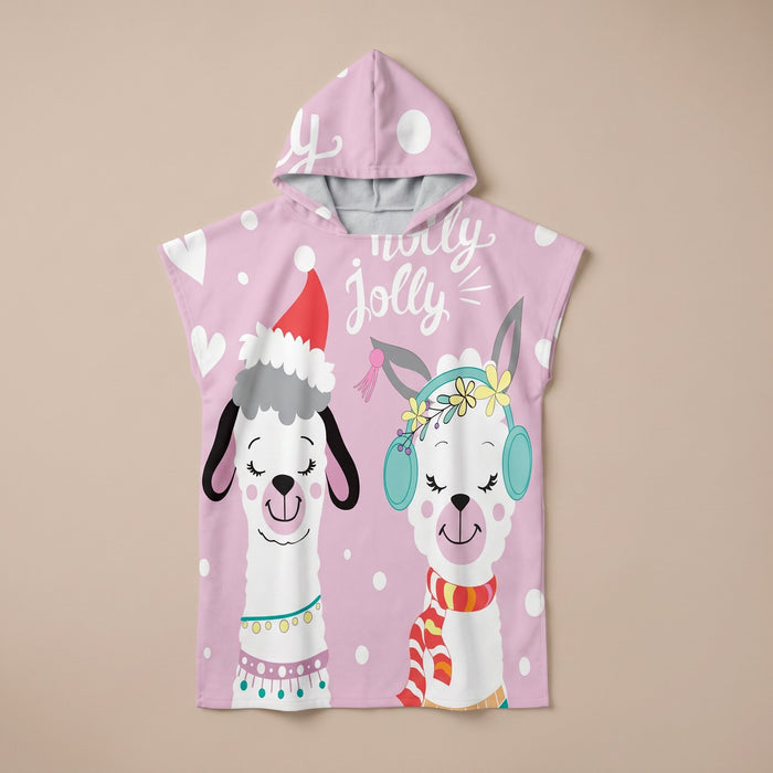 Poncho serviette à capuche motif lamas de Noël, présenté à plat sur un fond uni rose clair.