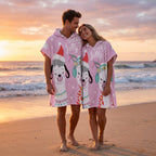 Poncho serviette à capuche motif lamas de Noël, porté par un couple souriant sur une plage au coucher du soleil.