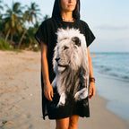 Poncho serviette à capuche motif lion noir et blanc, porté par une femme en plan moyen sur la plage.