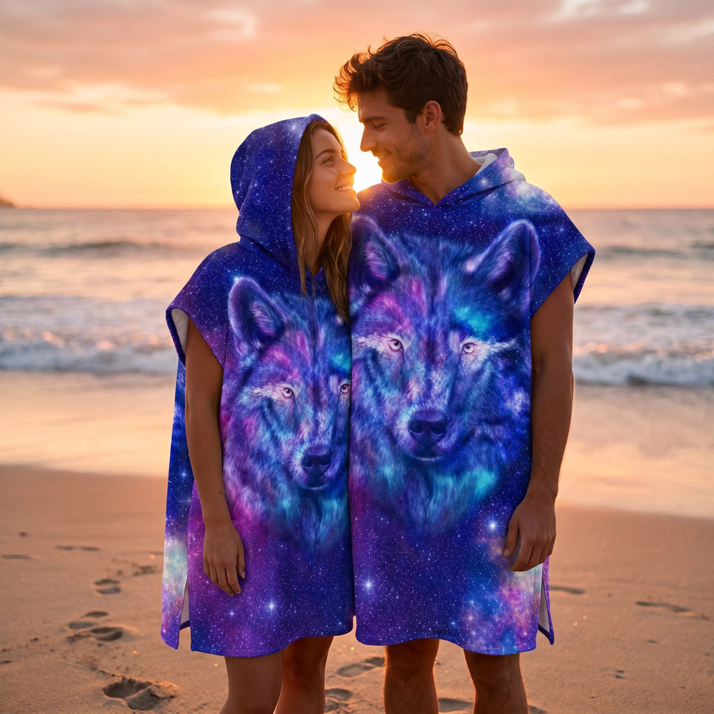 Poncho serviette a capuche motif Loup cosmos violet, porté par un couple souriant sur une plage au coucher du soleil.