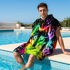 Poncho serviette à capuche motif Loup néon, porté par un homme assis au bord d'une piscine les pieds dans l'eau.