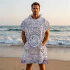 Poncho serviette à capuche motif mandala dentelle violet porté par un homme, les mains dans les poches.