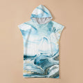 Poncho serviette a capuche motif marbre bleu givré, présenté à plat sur un fond uni beige clair.