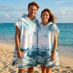 Poncho serviette a capuche motif marbre bleu givré, porté par un homme et une femme souriants sur une plage ensoleillée.