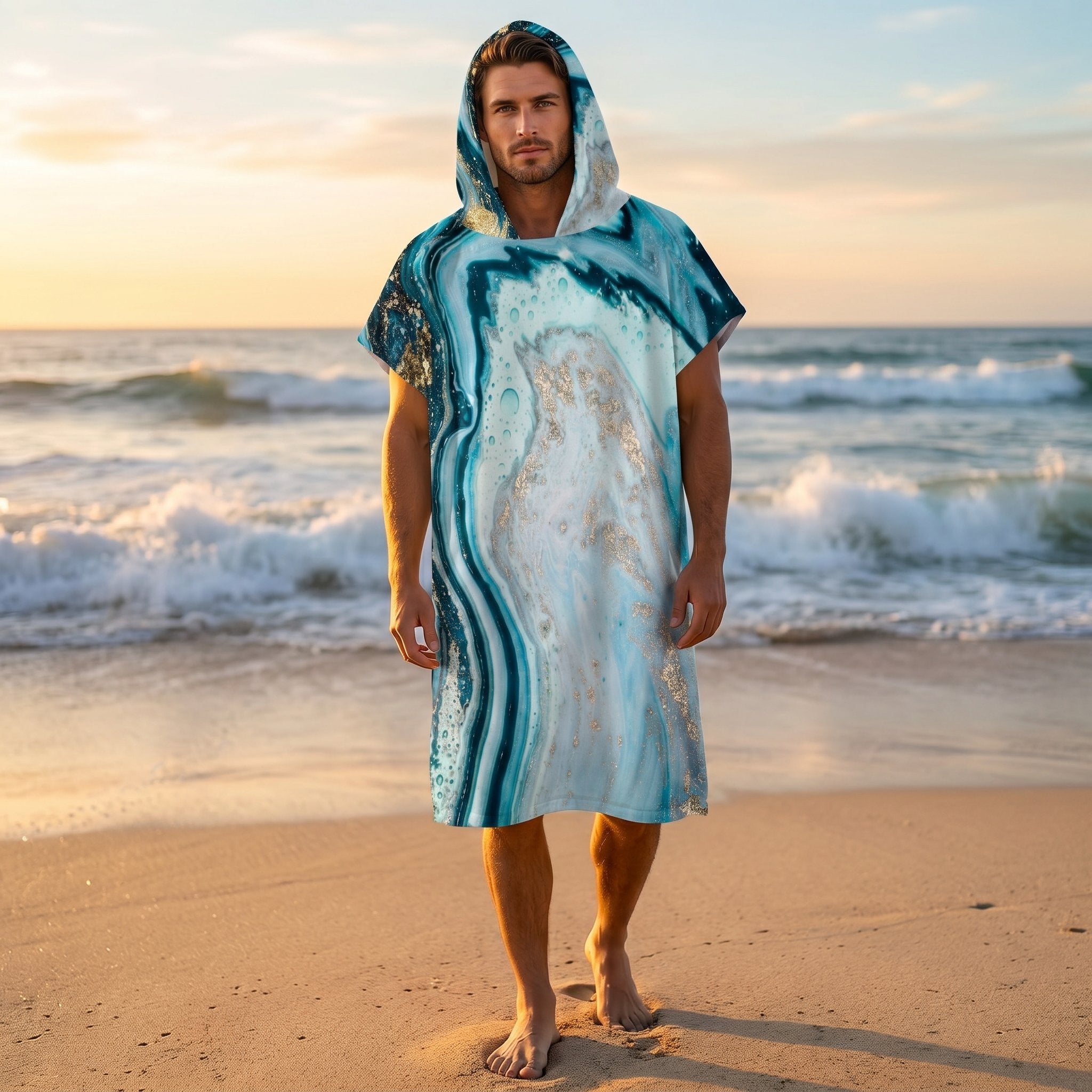 Poncho serviette à capuche motif marbre turquoise doré, porté par un homme sur une plage au coucher du soleil.