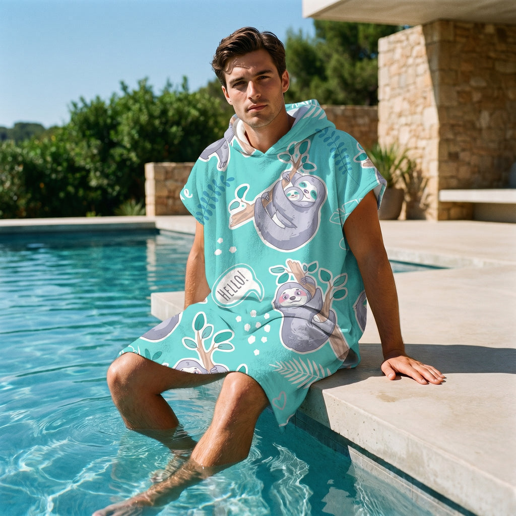 Poncho serviette a capuche motif paresseux turquoise, porte par un homme assis au bord d'une piscine.