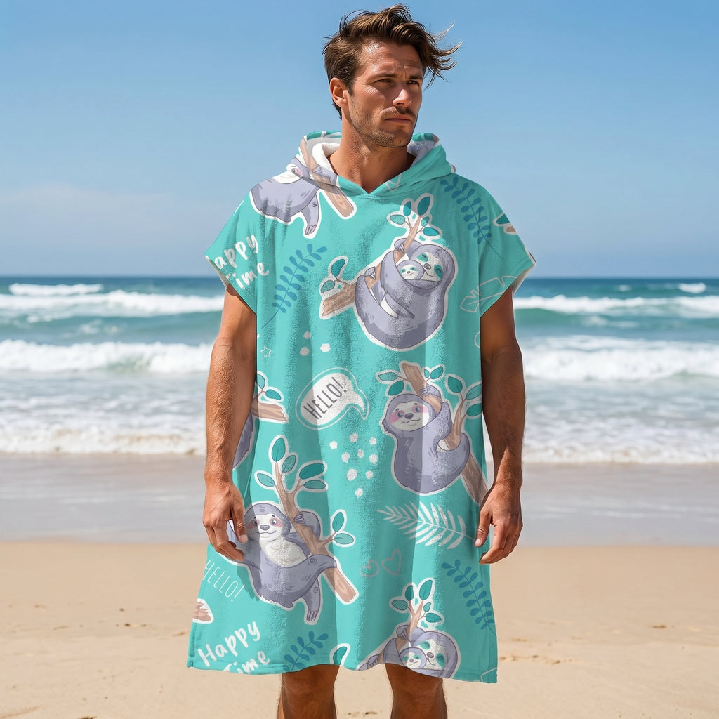 Poncho serviette a capuche motif paresseux turquoise, porte par un homme debout sur une plage de sable.