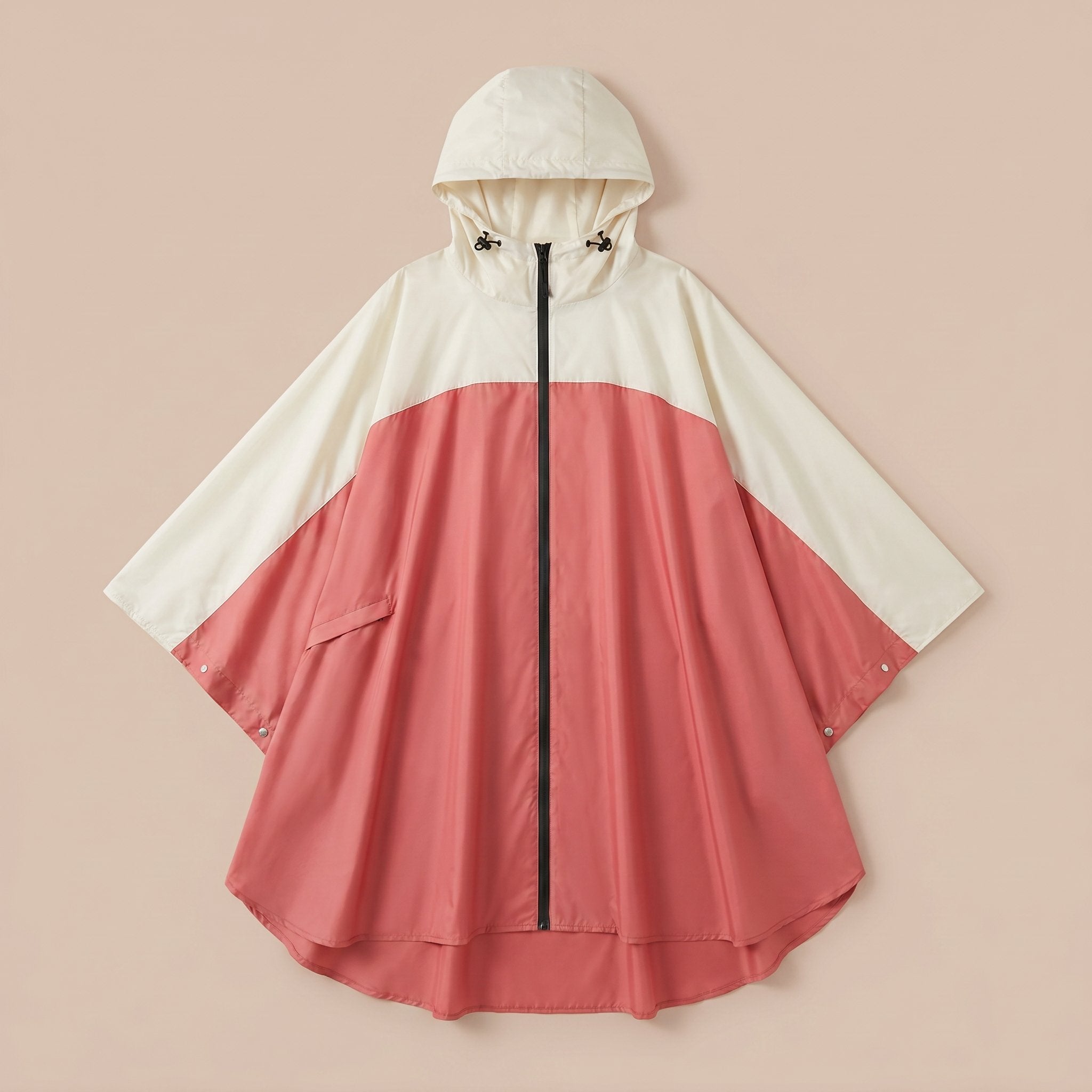 Poncho vélo crème et rose, avec sa capuche, présenté à plat sur un fond uni.