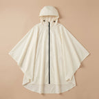 Poncho vélo crème uni, posé à plat sur un fond beige clair, montrant sa forme ample.