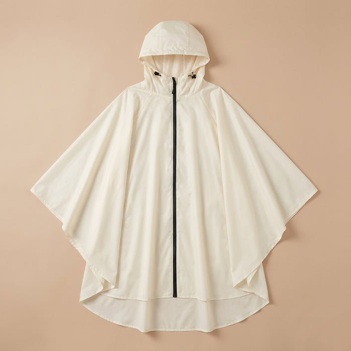 Poncho vélo crème uni, posé à plat sur un fond beige clair, montrant sa forme ample.