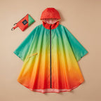 Poncho vélo dégradé arc-en-ciel posé à plat sur un fond uni, avec sa pochette de rangement assortie.