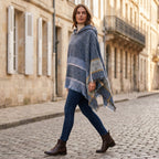 Pull poncho à capuche femme gris-bleu, porté de profil par une femme en mouvement, soulignant sa coupe et les motifs latéraux