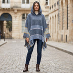 Pull poncho à capuche femme gris-bleu, porté de face par une femme en extérieur, révélant sa coupe ample et ses motifs